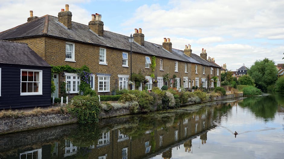 A row of traditional terraced houses in Abbeville Village with brick facades and white window frames, featuring blue-painted external stairs leading to first-floor entrances. The ground-level entrance